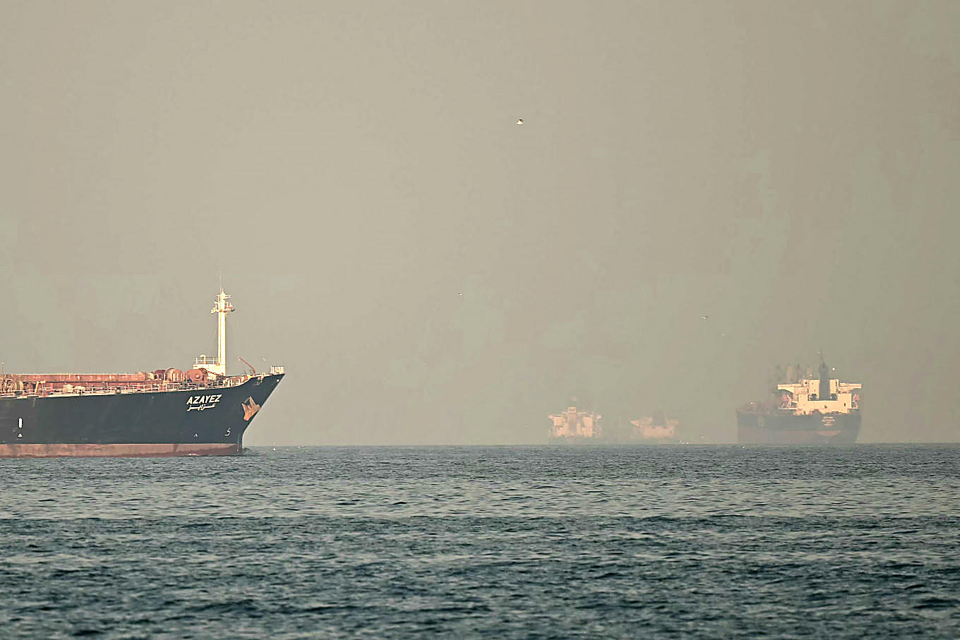 Tankers on a hazy sea in the Middle East, in color. No figures in the frame.