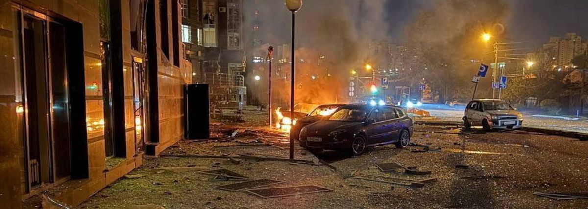 Cars burn on a Belgorod street at night, with broken glass and debris in the foreground. No people are in the frame.
