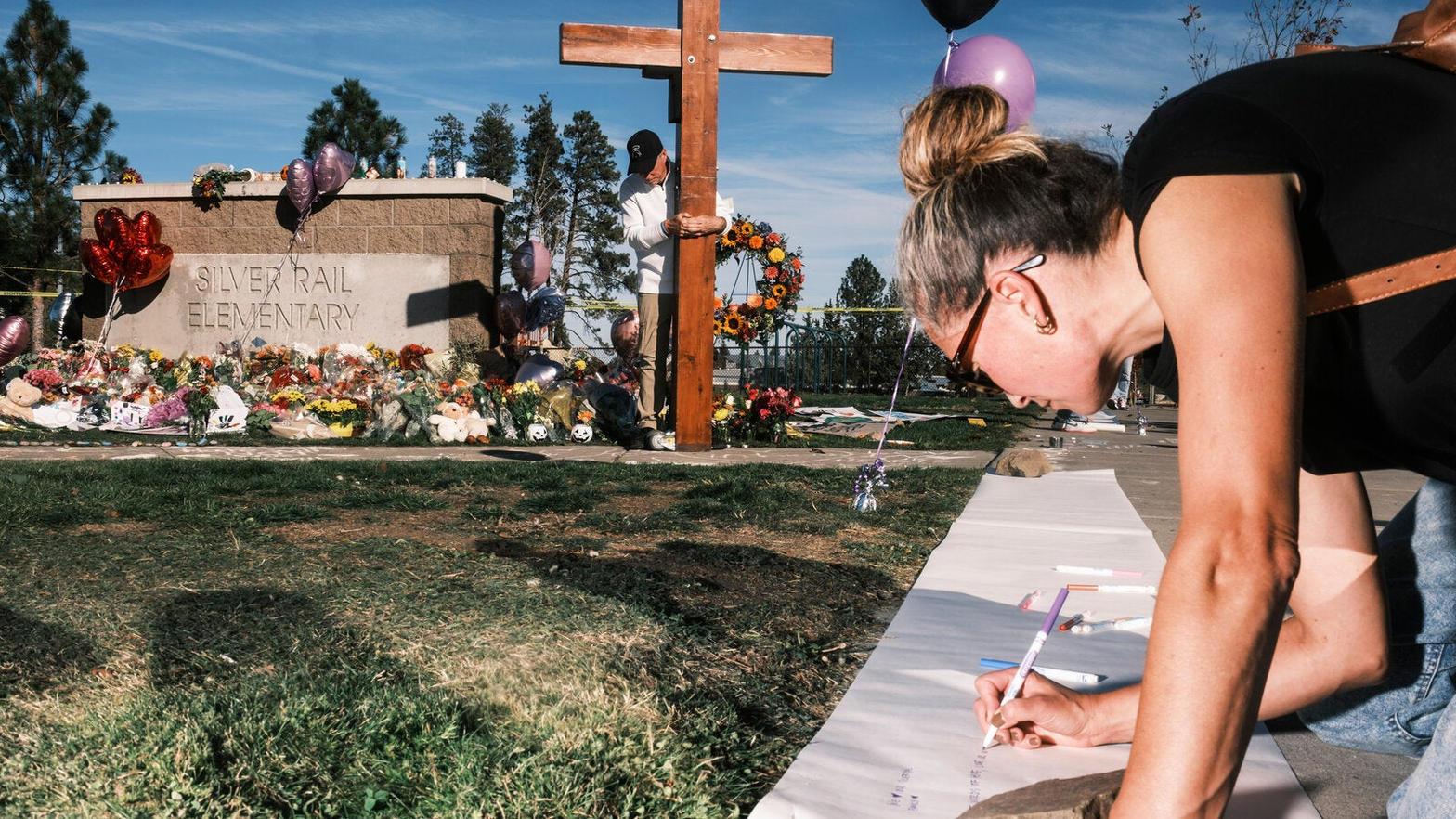 A woman writes at a memorial outside Silver Rail Elementary in Bend the day after the shooting.