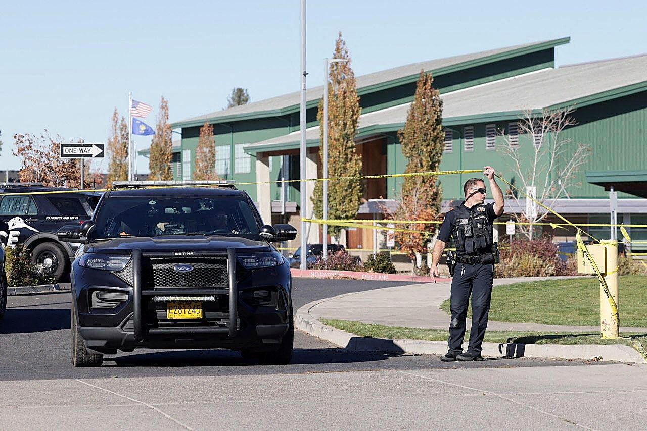 An officer holds police tape outside Silver Rail Elementary in Bend after a shooting killed four.