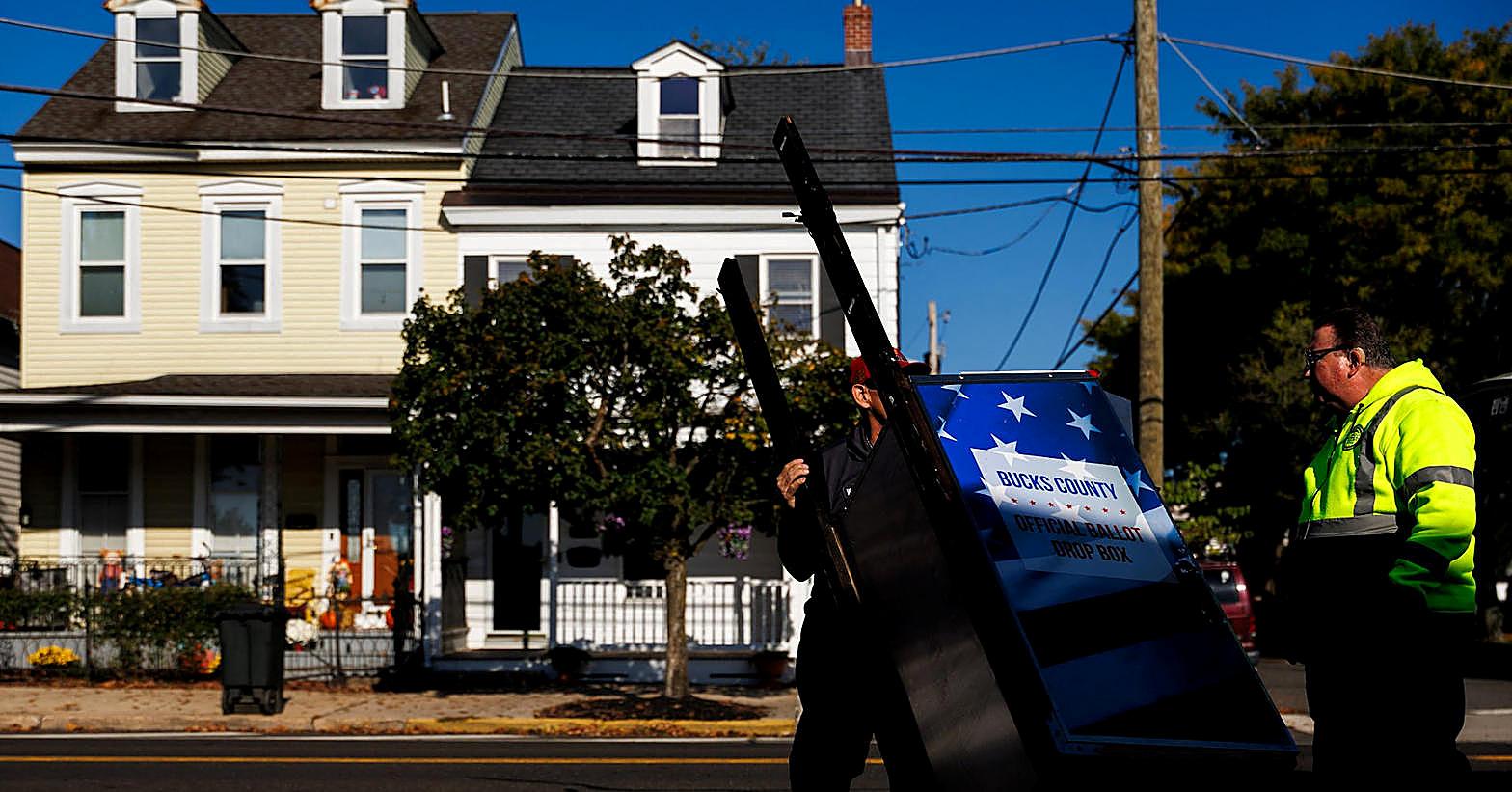 Workers move a ballot drop box on a residential street as investigators look at suspicious letters to election offices.