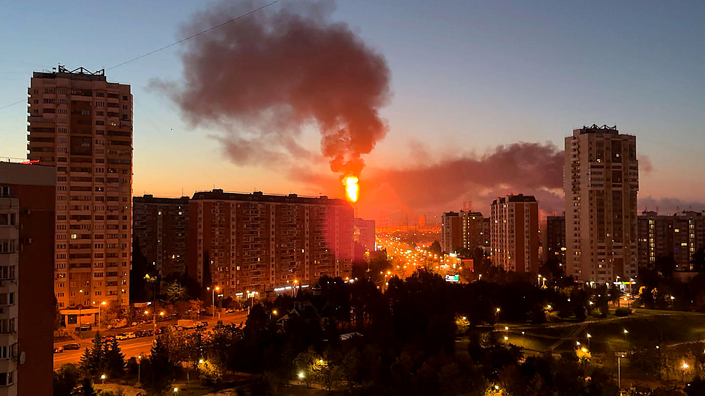 A column of fire and red smoke over Moscow apartment blocks at dusk, in color. Wire photograph.