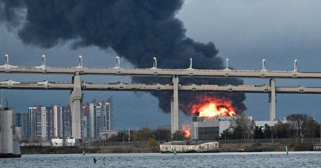 Flame and black smoke rise from a St. Petersburg oil terminal on Sunday, seen past a bridge.