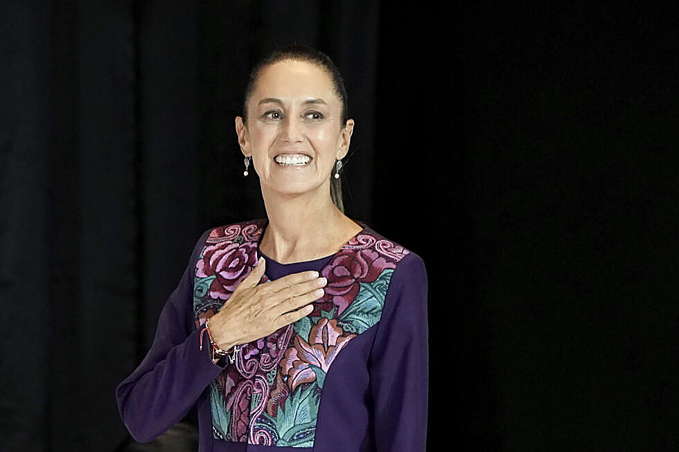 President Claudia Sheinbaum, hand on her chest, full color, embroidered jacket. Wire photograph.